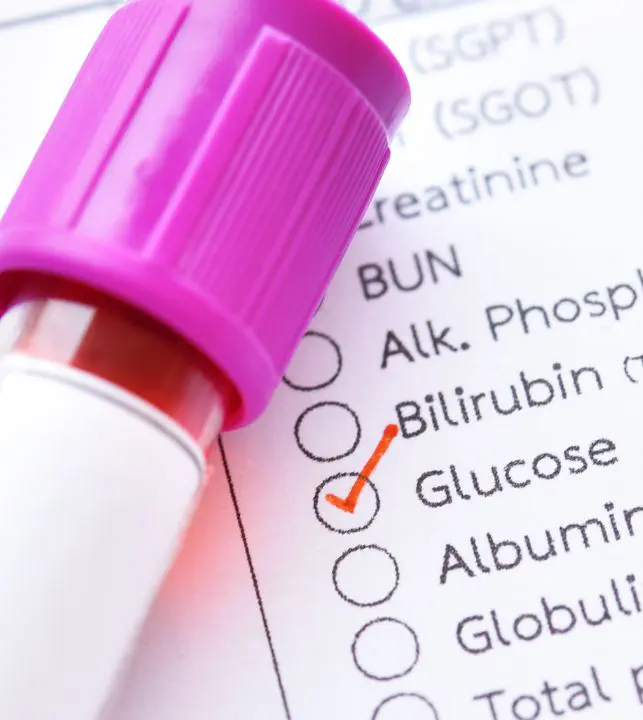 Muestra de sangre sobre un formulario de laboratorio con la prueba de Glucosa marcada