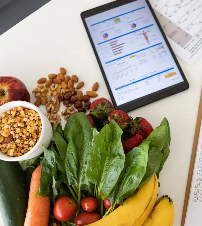 Alimentos frescos y naturales junto a una tableta mostrando un plan nutricional digital y métricas de salud